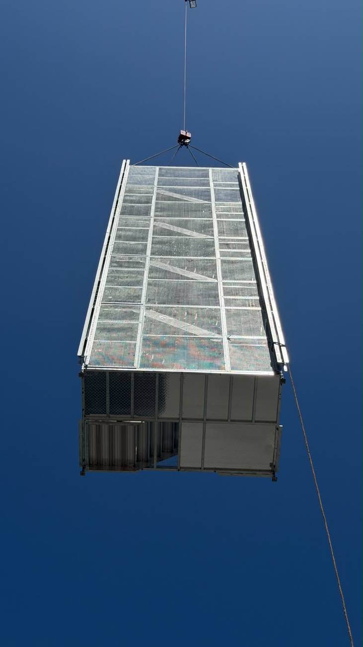 Enclosed stretcher stair module suspended during installation